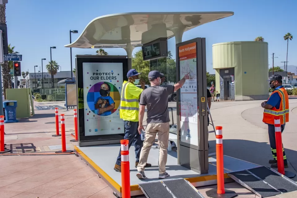 Two men looking at wayfinding sign on prototype bus shelter in North Hollywood, California.